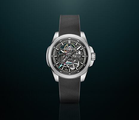 NORQAIN skeleton watch with a grey strap against a dark teal background.
