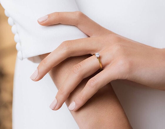 Elegant hand wearing a Tulip Setting diamond engagement ring in yellow gold, exclusive Fraser Hart design